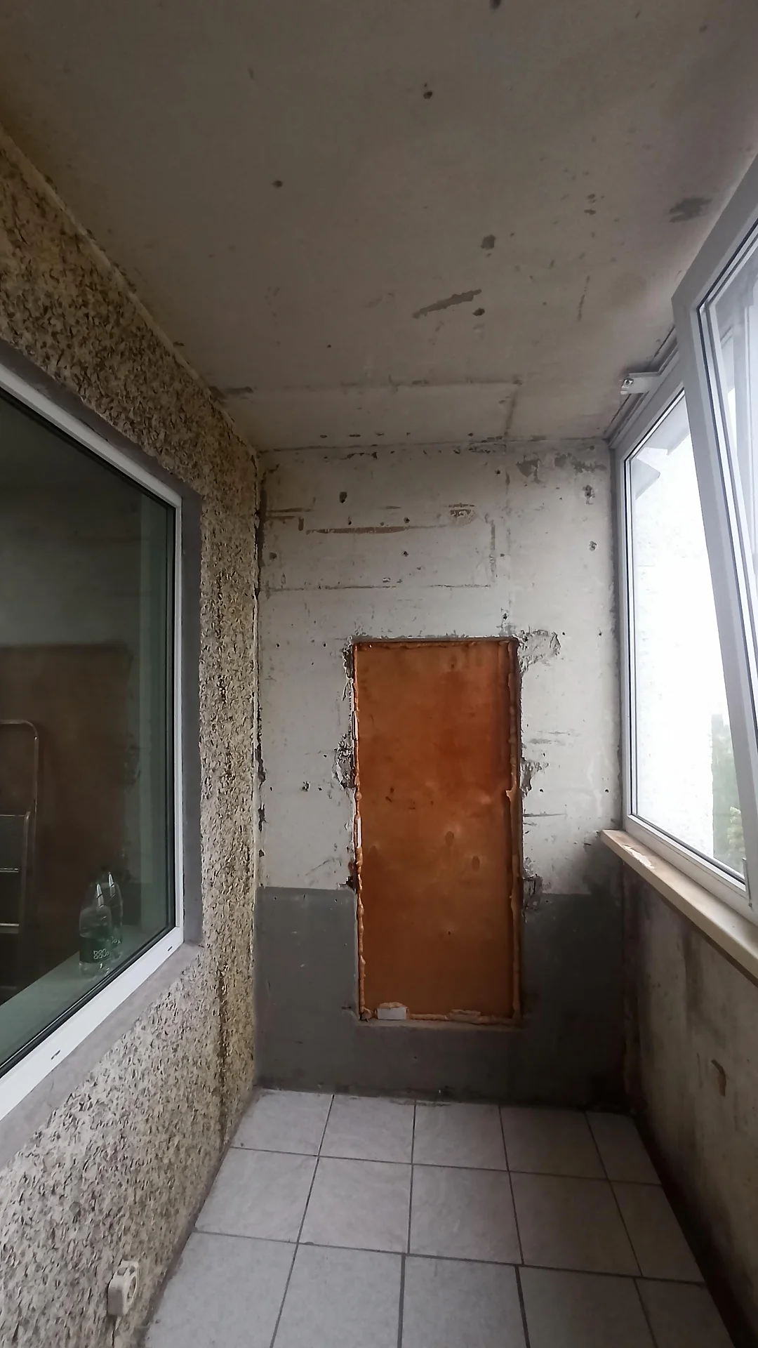 Старый пол на балконе с плиткой и заколоченным проемом